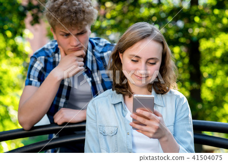 Beautiful brunette girl in summer park on nature. In hands of holding smartphone communicates in Beautiful brunette girl in summer park on nature. In hands of holding smartphone communicates in 41504075