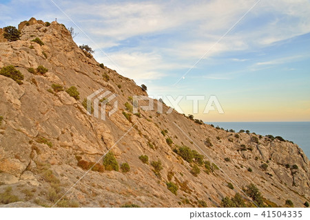 Rocky hillside by the sea at sunset Rocky hillside by the sea at sunset 41504335