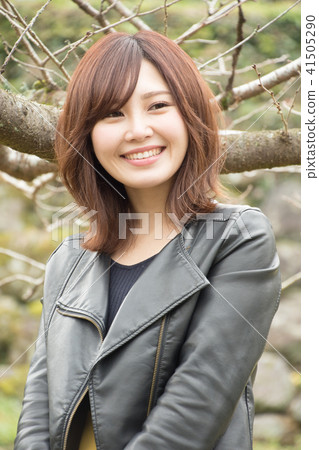 A woman standing in front of a tree A woman standing in front of a tree 41505290