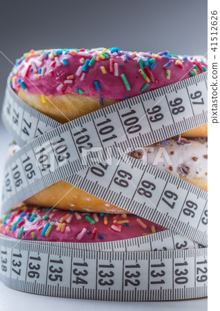 Three colorful donuts wrapped in a tailors tape. Three colorful donuts wrapped in a tailors tape. 41512626