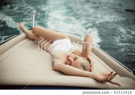 Beautiful young sexy blonde woman is wearing white swimsuit doing summer trip on a yacht 41513418