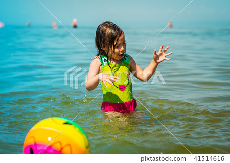 little girl gets wet after playing a ball in the sea 41514616