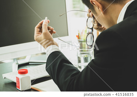 Businessman with pills in his hand at workplace Businessman with pills in his hand at workplace 41516835