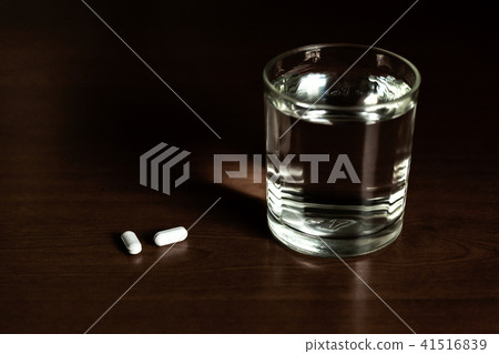Concept glass of water and pills on wooden table Concept glass of water and pills on wooden table 41516839