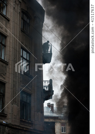 fire during urban riots, a lot of smoke. Protester watching from the balcony of the fire 41517637