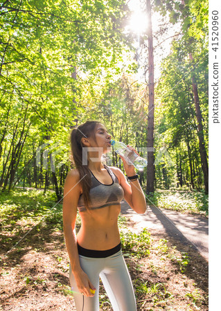 Young woman drinking water after running outdoors 41520960