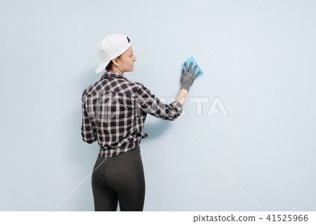 Girl painter, designer and worker paints a roller and brush the wall. Smiling, working with pleasure 41525966