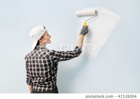 Girl painter, designer and worker paints a roller and brush the wall. Smiling, working with pleasure 41526004
