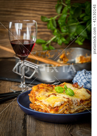 Piece of tasty hot lasagna with red wine. Piece of tasty hot lasagna with red wine. 41530148