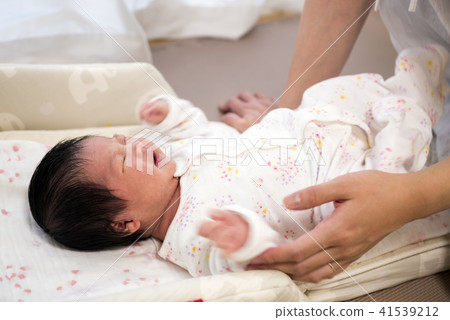 哭泣的嬰兒躺在她的背上和母親的手上 哭泣的嬰兒躺在她的背上和母親的手上 41539212