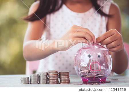 asian girl putting money into piggy bank 41541756
