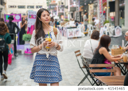 woman holding a cup of mango juice and shopping 41545465