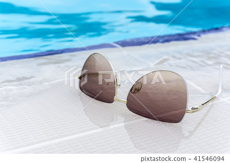 Summer sunglasses fashion concept, sunglasses on swimming edge, outdoor day light Summer sunglasses fashion concept, sunglasses on swimming edge, outdoor day light 41546094