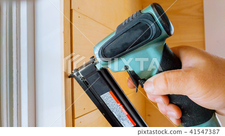 Carpenter brad using nail gun to moldings trim,   41547387