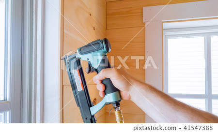 Carpenter brad using nail gun to molding  41547388