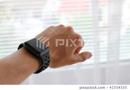 Man's hand with black smart watch in office Man's hand with black smart watch in office 41554335