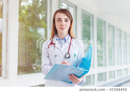 Portrait of a young female doctor with a stethoscope and folder on the consultation in clinic Portrait of a young female doctor with a stethoscope and folder on the consultation in clinic 41568450