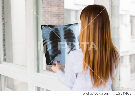 A female doctor examines an x ray of shot of the lungs. View from the back A female doctor examines an x ray of shot of the lungs. View from the back 41568463
