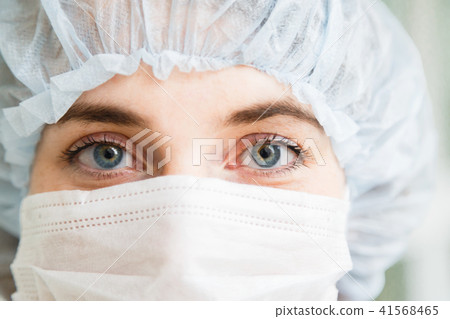 Close-up portrait of young female surgeon doctor or intern wearing protective mask and hat Close-up portrait of young female surgeon doctor or intern wearing protective mask and hat 41568465