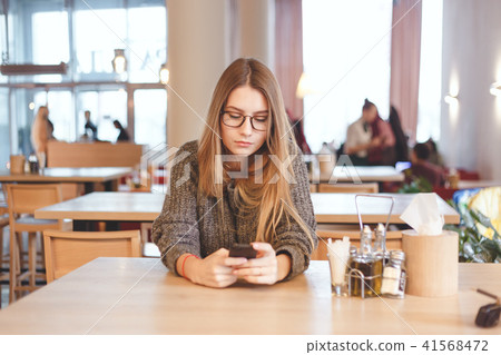 Charming woman with beautiful smile reading good news on mobile phone during rest in cafe Charming woman with beautiful smile reading good news on mobile phone during rest in cafe 41568472