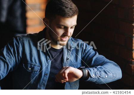 Young businessman look at the watchl in cafe while he use a laptop 41591454