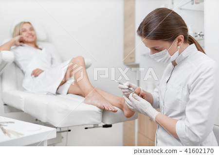 Podiatrist doctor cleaning foot from callus. Podiatrist doctor cleaning foot from callus. 41602170