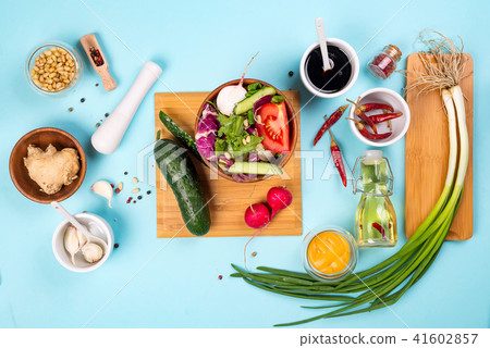 Salad making. Cutlery and dressing ingredients for fresh salad on light blue background, top view 41602857