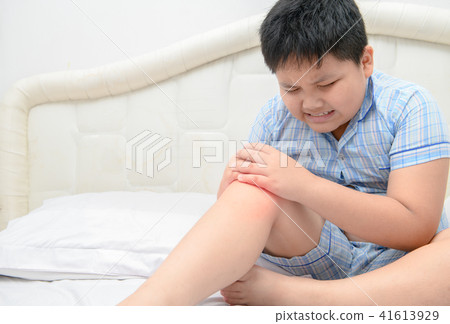 Obese boy suffering from knee pain and sit on bed, 41613929