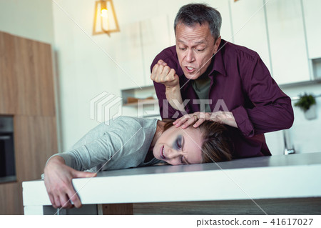 Crazy husband kicking his wife head in the table 41617027