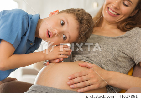 Curious dark-eyed boy listening to pregnant tummy 41617861