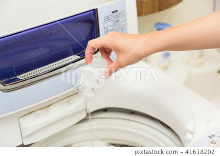 A woman putting detergent in a washing machine 41618202
