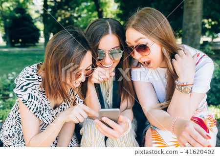 Happy friends in the park on a sunny day . Summer lifestyle portrait of three multiracial women Happy friends in the park on a sunny day . Summer lifestyle portrait of three multiracial women 41620402