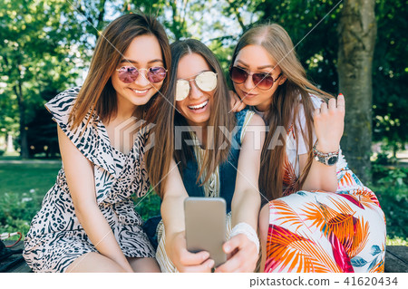 Happy friends in the park on a sunny day . Summer lifestyle portrait of three multiracial women Happy friends in the park on a sunny day . Summer lifestyle portrait of three multiracial women 41620434