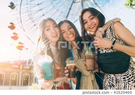 Summer lifestyle portrait multiracial women enjoy nice day, holding glasses of milkshakes. Happy Summer lifestyle portrait multiracial women enjoy nice day, holding glasses of milkshakes. Happy 41620469