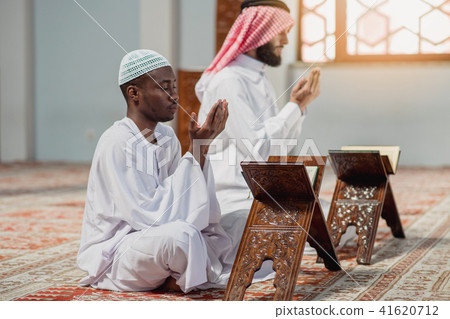 Two religious muslim man praying together inside the mosque Two religious muslim man praying together inside the mosque 41620712