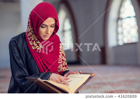 Muslim Woman Reading Koran Or Quran Wearing Traditional Dress At The Mosque Muslim Woman Reading Koran Or Quran Wearing Traditional Dress At The Mosque 41620889