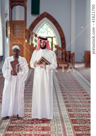 Two religious muslim man walking together inside the mosque Two religious muslim man walking together inside the mosque 41621700