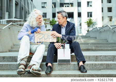 Long-haired elderly hippy man telling fired man he is not alone 41621706