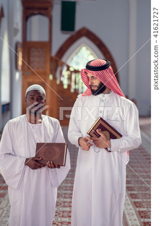 Two religious muslim man walking together inside the mosque Two religious muslim man walking together inside the mosque 41621727