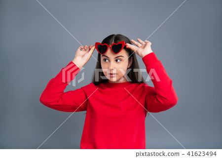 Cute teenage girl removing heart-shaped sunglasses 41623494