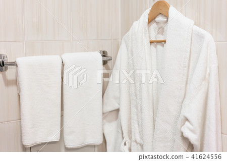 Clean white towel and bathrobe on a hanger prepared to use. Bathroom Inside rooms of a apartment or 41624556