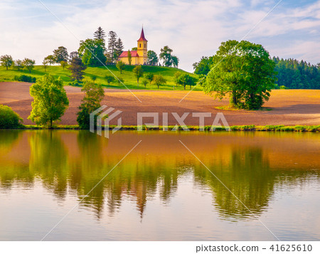 Romantic landscape with small church on the hill reflected in the pond. Sunny summer day with blue 41625610