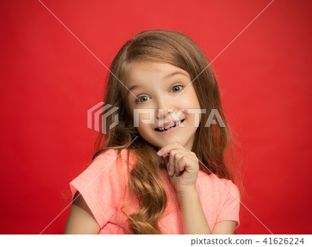 The happy teen girl standing and smiling against red background. The happy teen girl standing and smiling against red background. 41626224