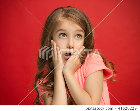 Beautiful teen girl looking suprised isolated on red 41626229