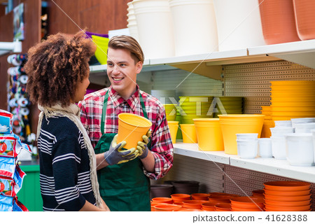Customer buying plastic pots at the advice of a helpful worker in flower shop Customer buying plastic pots at the advice of a helpful worker in flower shop 41628388