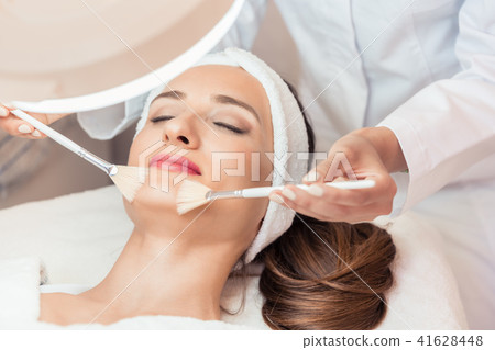 Beautiful woman during anti-aging facial massage in a modern cosmetic center Beautiful woman during anti-aging facial massage in a modern cosmetic center 41628448