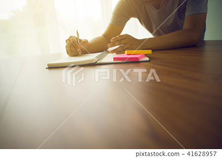 man writing on paper notebook or old diary at home man writing on paper notebook or old diary at home 41628957