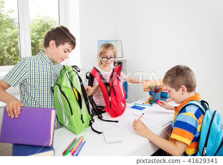 Children with rucksacks sitting on the stairs near school 41629341