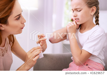 Nice pleasant woman looking at her daughters bruise 41629657