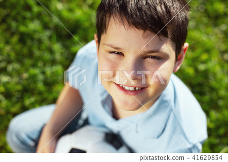 Exuberant boy sitting on the grass with his ball Exuberant boy sitting on the grass with his ball 41629854
